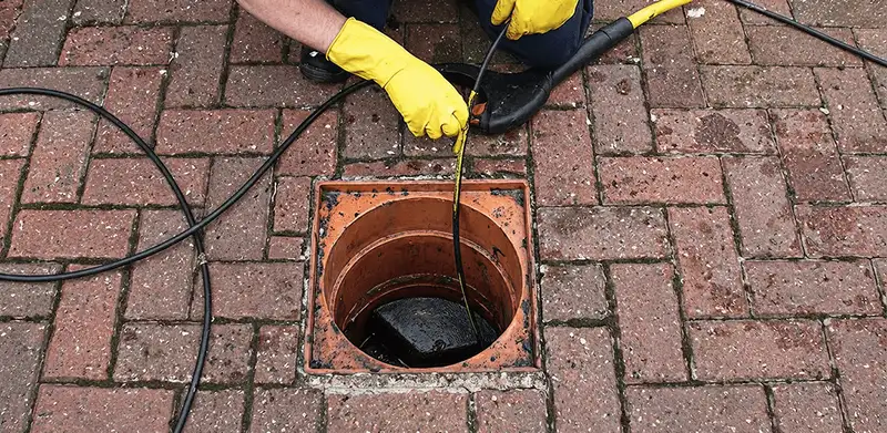 Drain cleaning technician using a drain snake to clear a clogged drain in Honolulu, HI