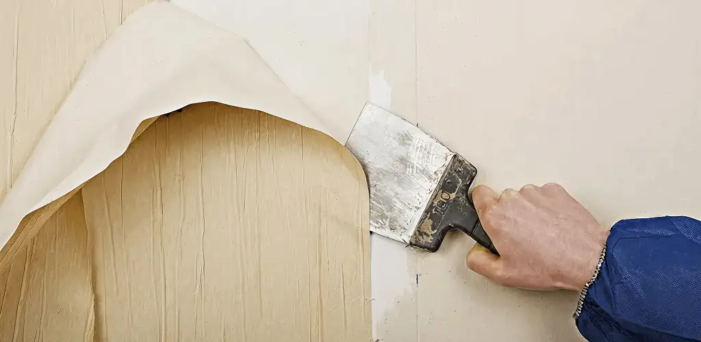 Handyman removing wallpaper with a scraper for wall preparation in Honolulu, HI
