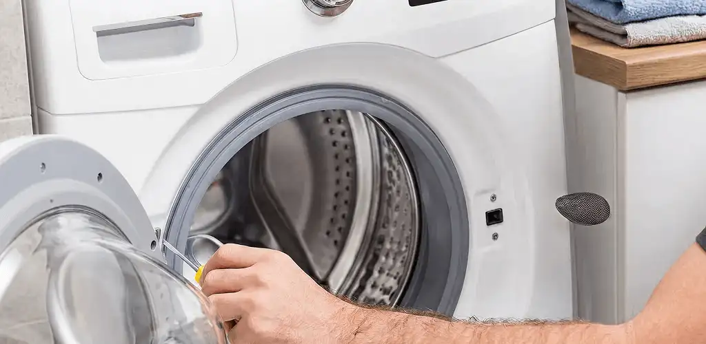 Handyman repairing a front-load washing machine and inspecting the drum in Honolulu, HI