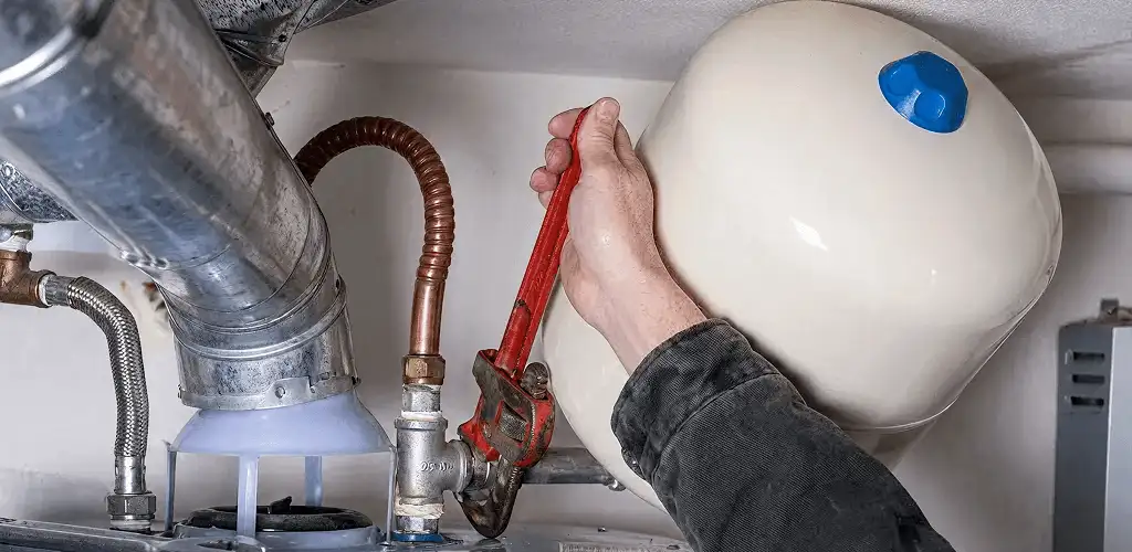 Water heater repair technician tightening plumbing connections near a tank unit in Honolulu, HI